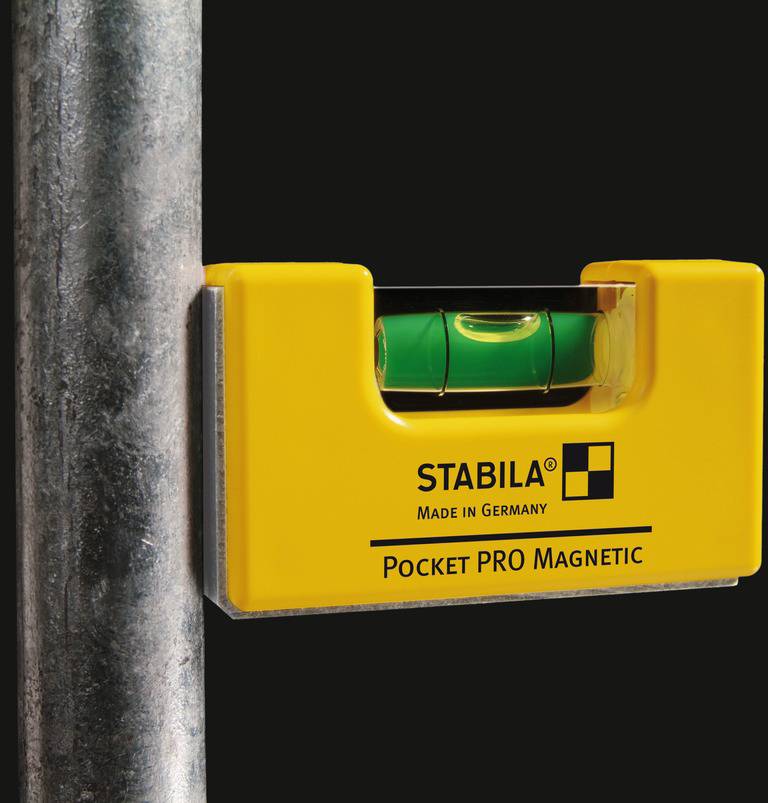 Rumena magnetna žepna libela znamke Stabila meri poravnavo navpičnega kovinskega cevi.