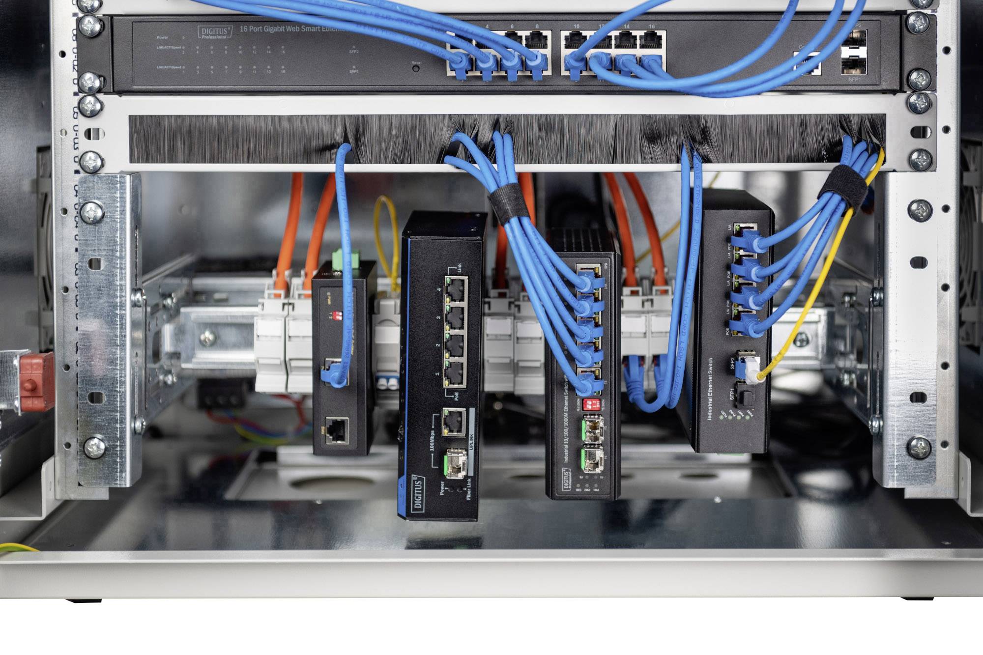 Omrežni vozlišči v strežniškem omari s povezanimi modrimi in oranžnimi kabli; centralna enota in upravljanje kablov sta jasno vidna.