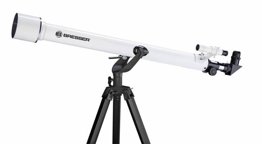 Belo teleskop z dolgim cevjem na črnem stojalu, primeren za amatersko astronomijo ali opazovanje zvezd.