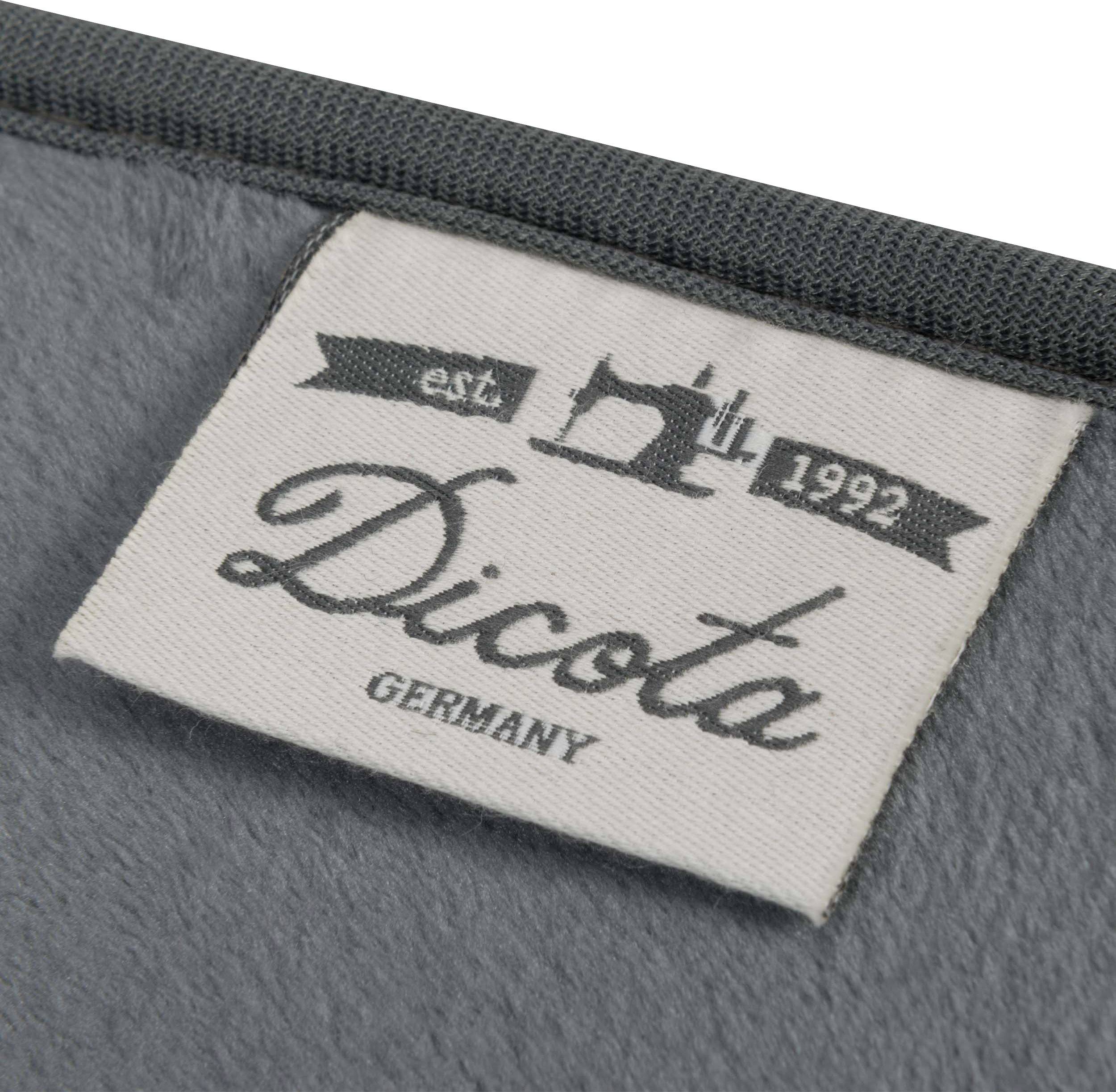 Siva tekstilna nalepka s črnim tiskom: 'Dicota GERMANY' in grafiko šivalne stroje z 'est. 1992'.