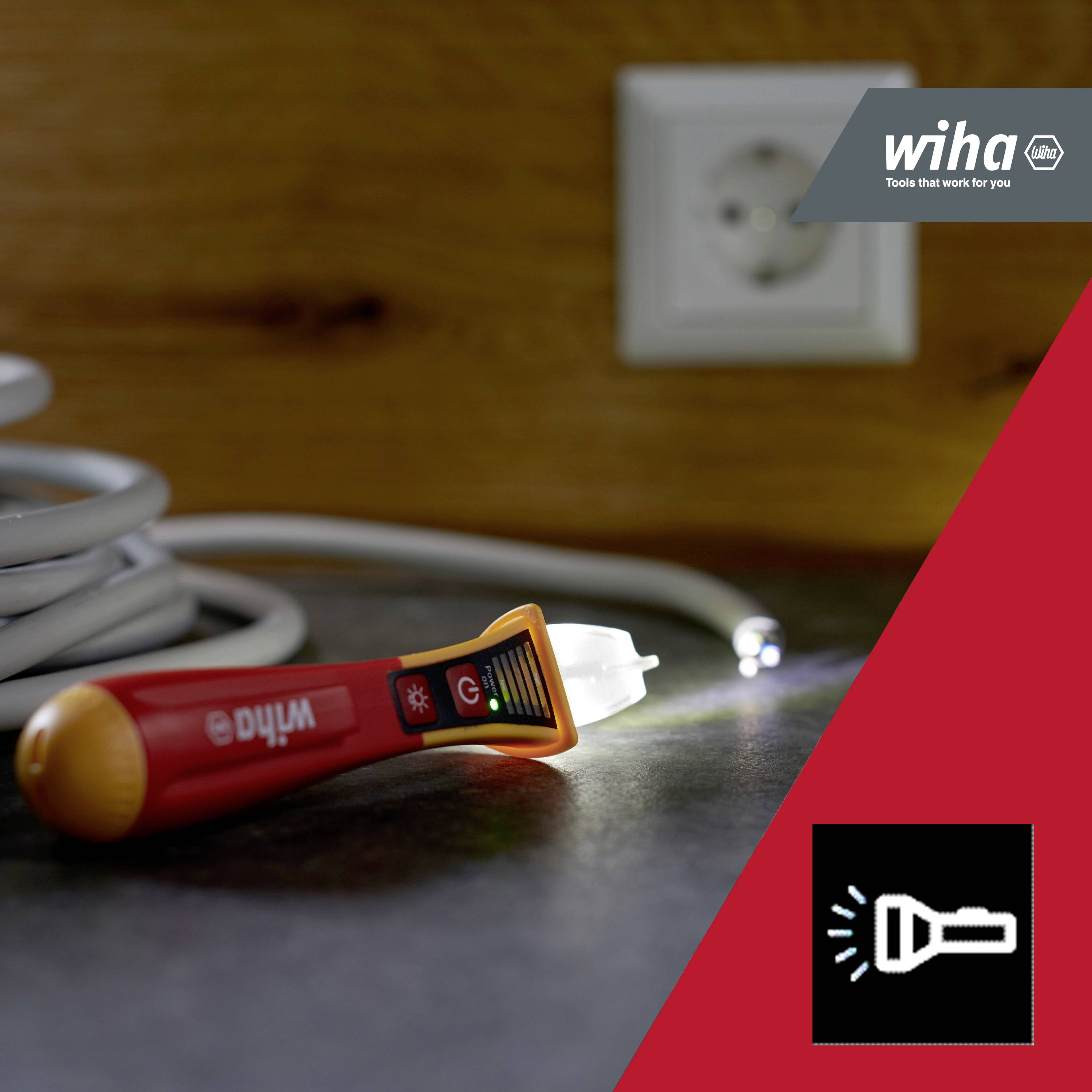 Električna vtičnica, kabel in svetleč preizkuševalec napetosti na mizi; v ozadju logotip podjetja Wiha, proizvajalca orodja.