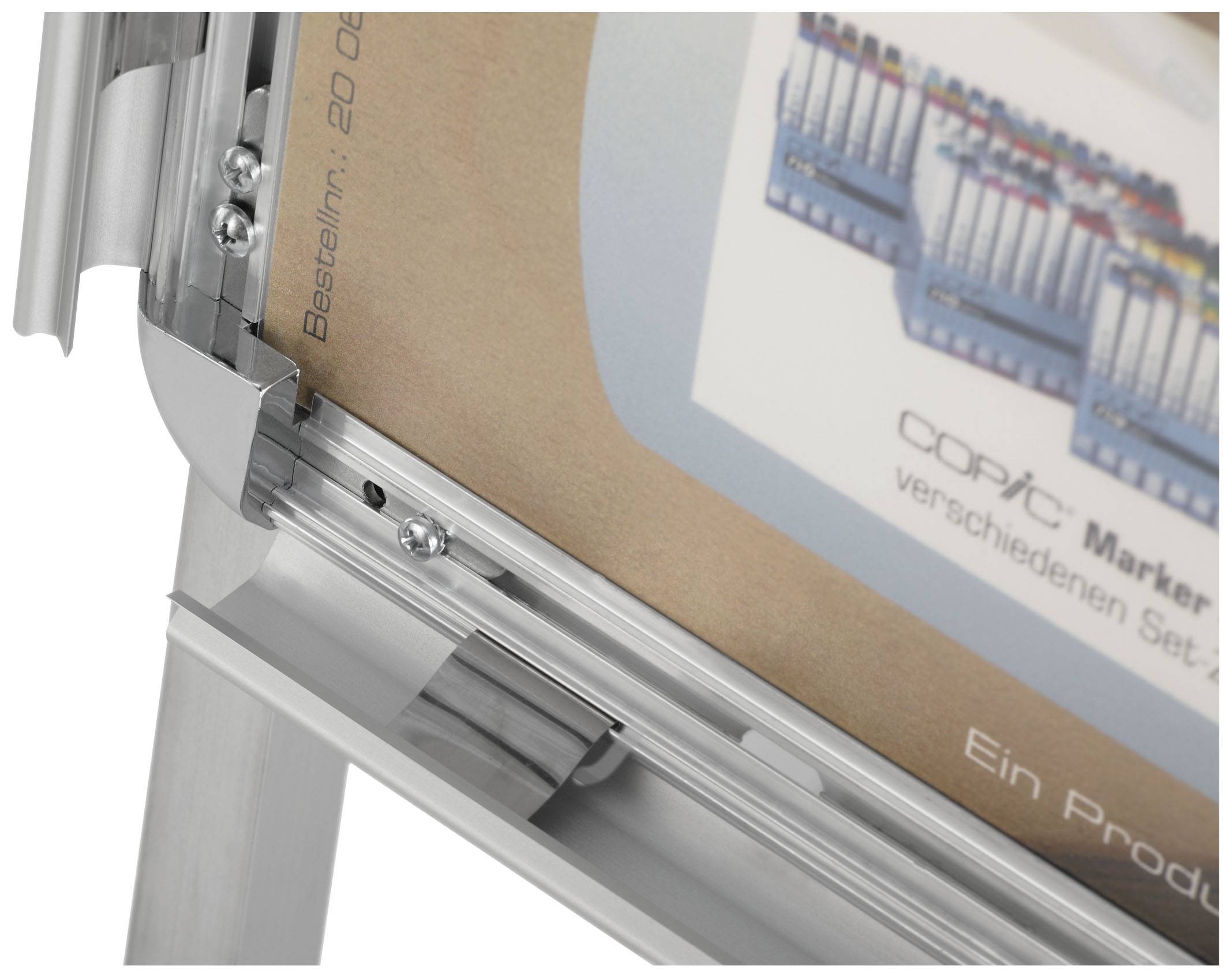 Srebrn zložljiv okvir prikazuje delno zakrito plakat. Zgoraj levo piše 'Naročilna št.: 20 06', spodaj desno pa 'Izdelek'.