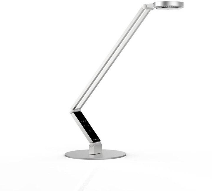 Moderna, srebrna namizna svetilka z nastavljivo roko in okroglo svetilno glavo na ploščatem, krožnem podstavku.