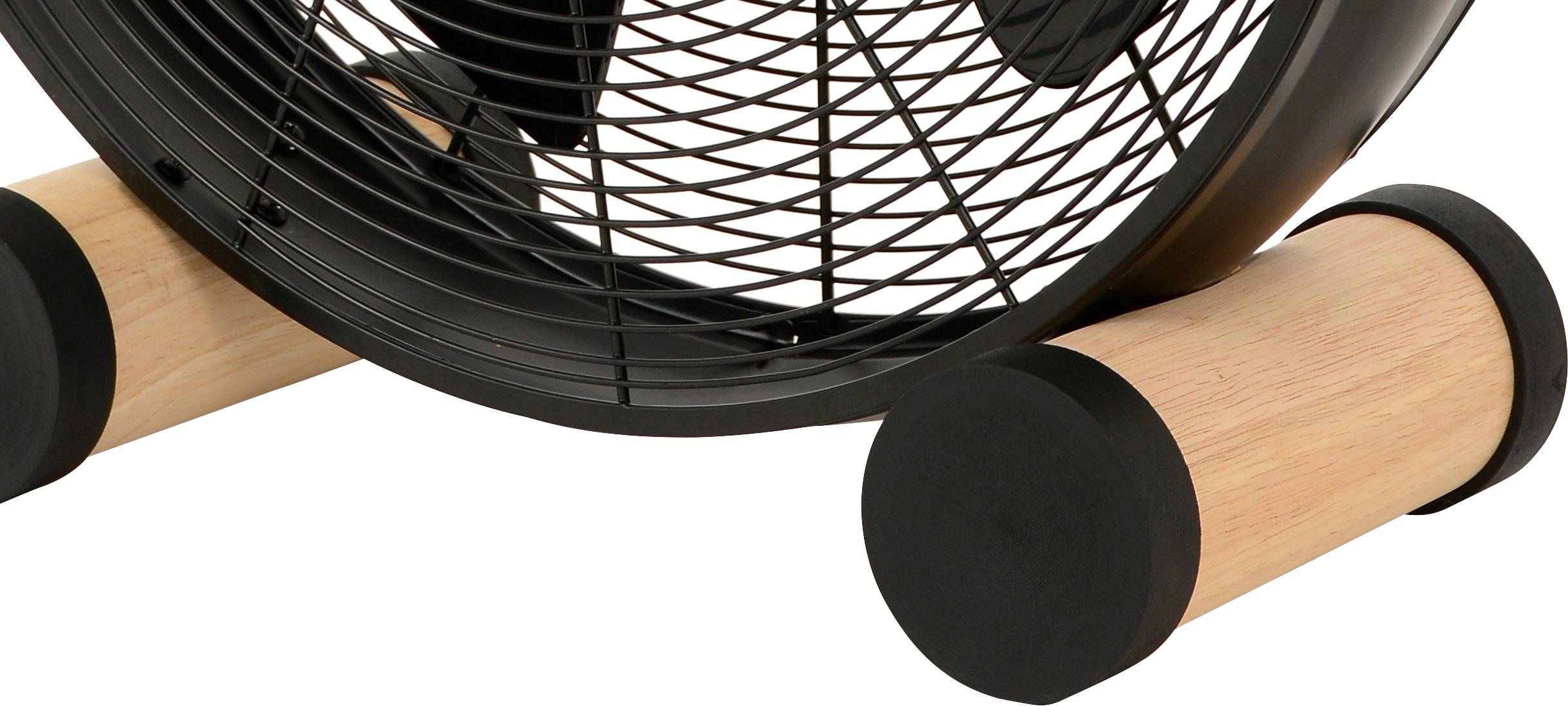 Črn ventilator z rešetko, nameščen na dveh valjih iz lesa.