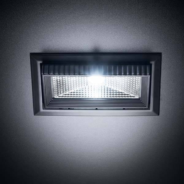 LED-svetilka v pravokotnem ohišju na stropu, ki prostor osvetljuje od zgoraj navzdol.
