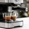 Espresso aparat hkrati pripravlja dva espresso napitka v prozornih skodelicah. Kovinski dizajn, sodoben kuhinjski pripomoček v akciji.