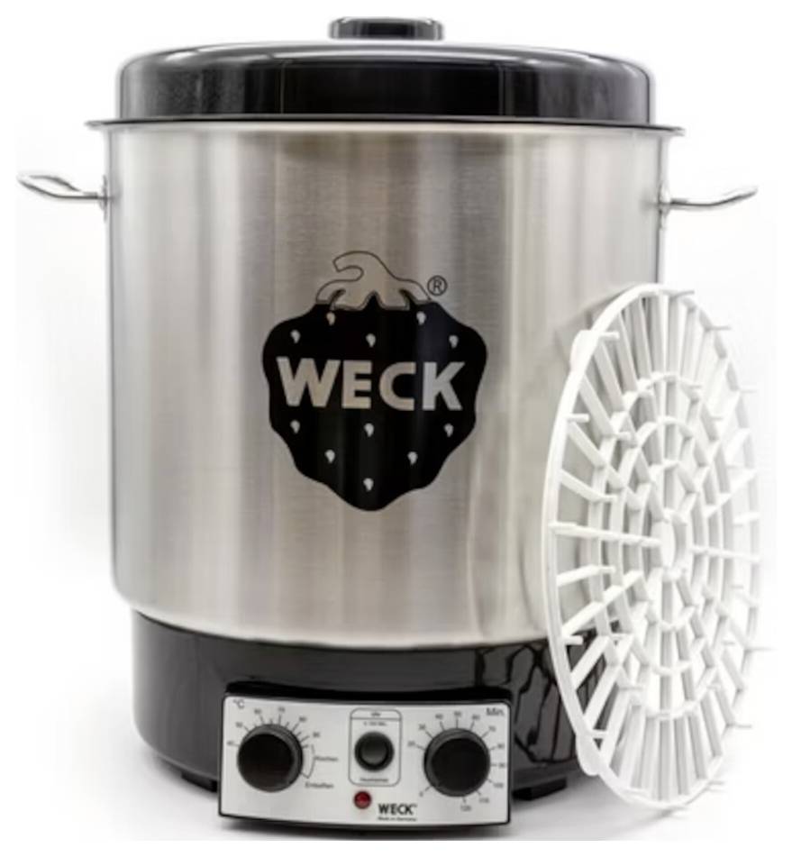 Lonec za vlaganje znamke 'WECK' iz nerjavečega jekla z ročaji, črnim pokrovom in temperaturno kontrolno gumbjo na dnu; poleg njega je postavljena bela plastična rešetka.