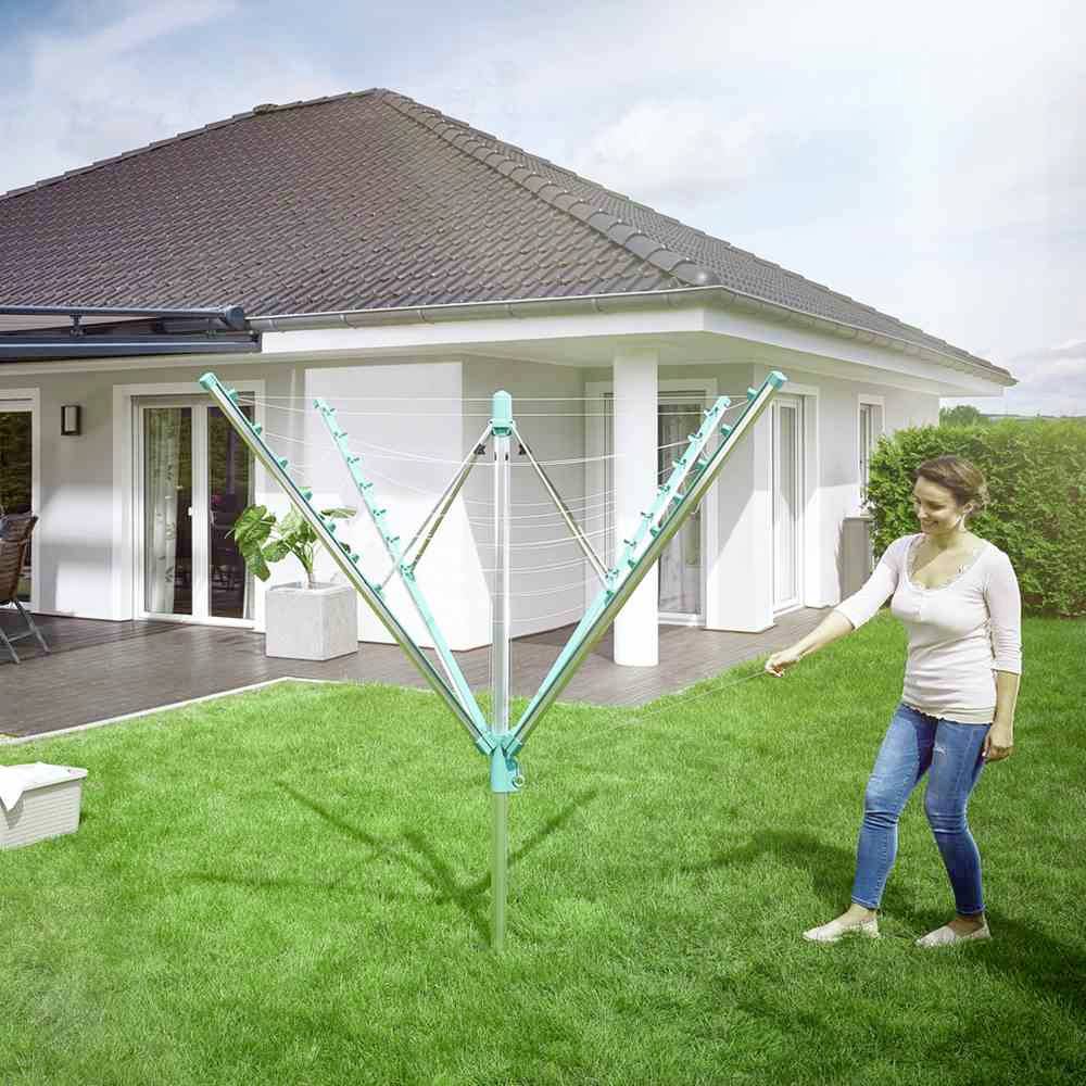 Ženska v vrtu gre proti sušilnemu vrvišču poleg sodobne samostojne hiše s teraso.