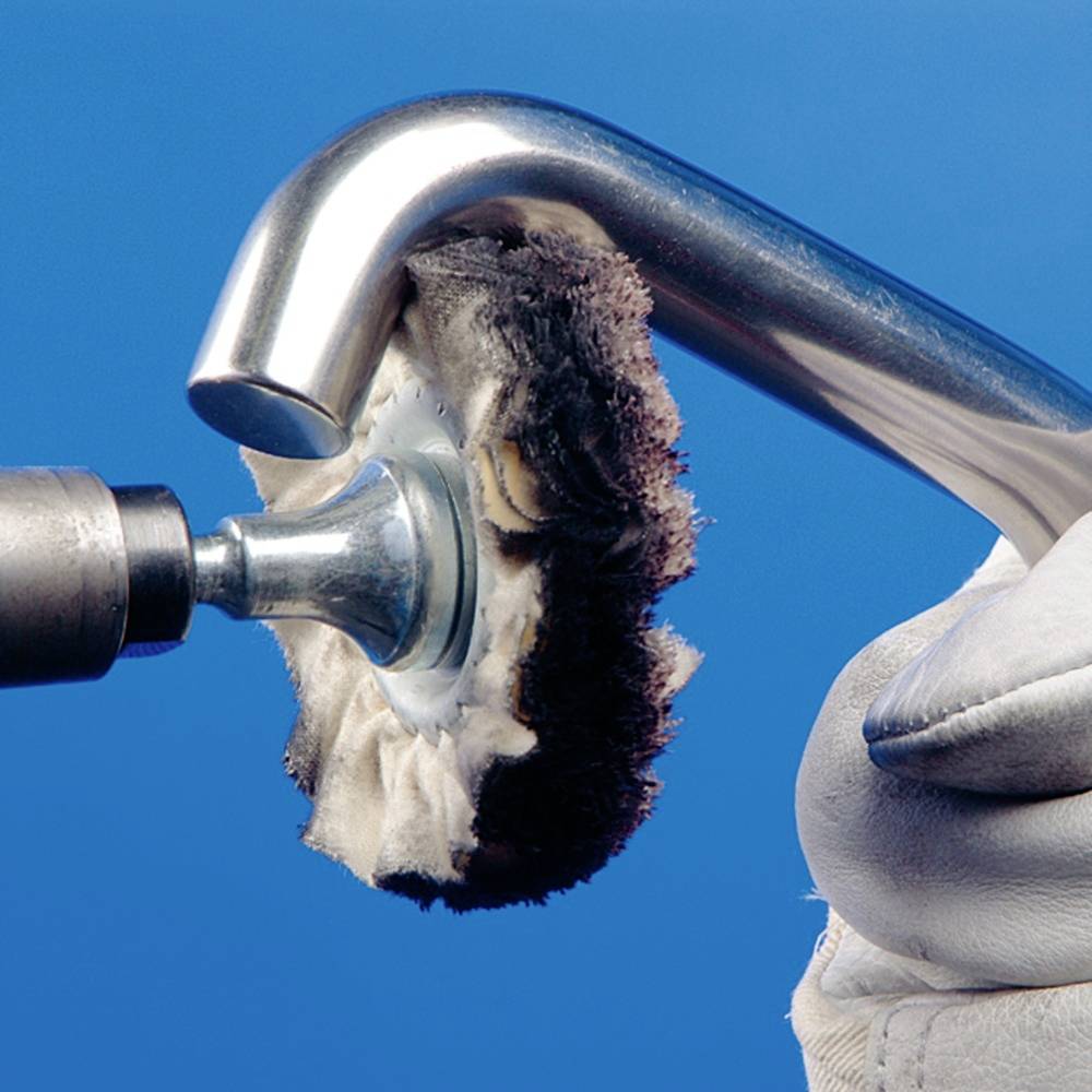 Kovinski polirec polira nerjavno jekleno površino z rotirajočo ploščo. Ena roka v rokavici drži orodje.