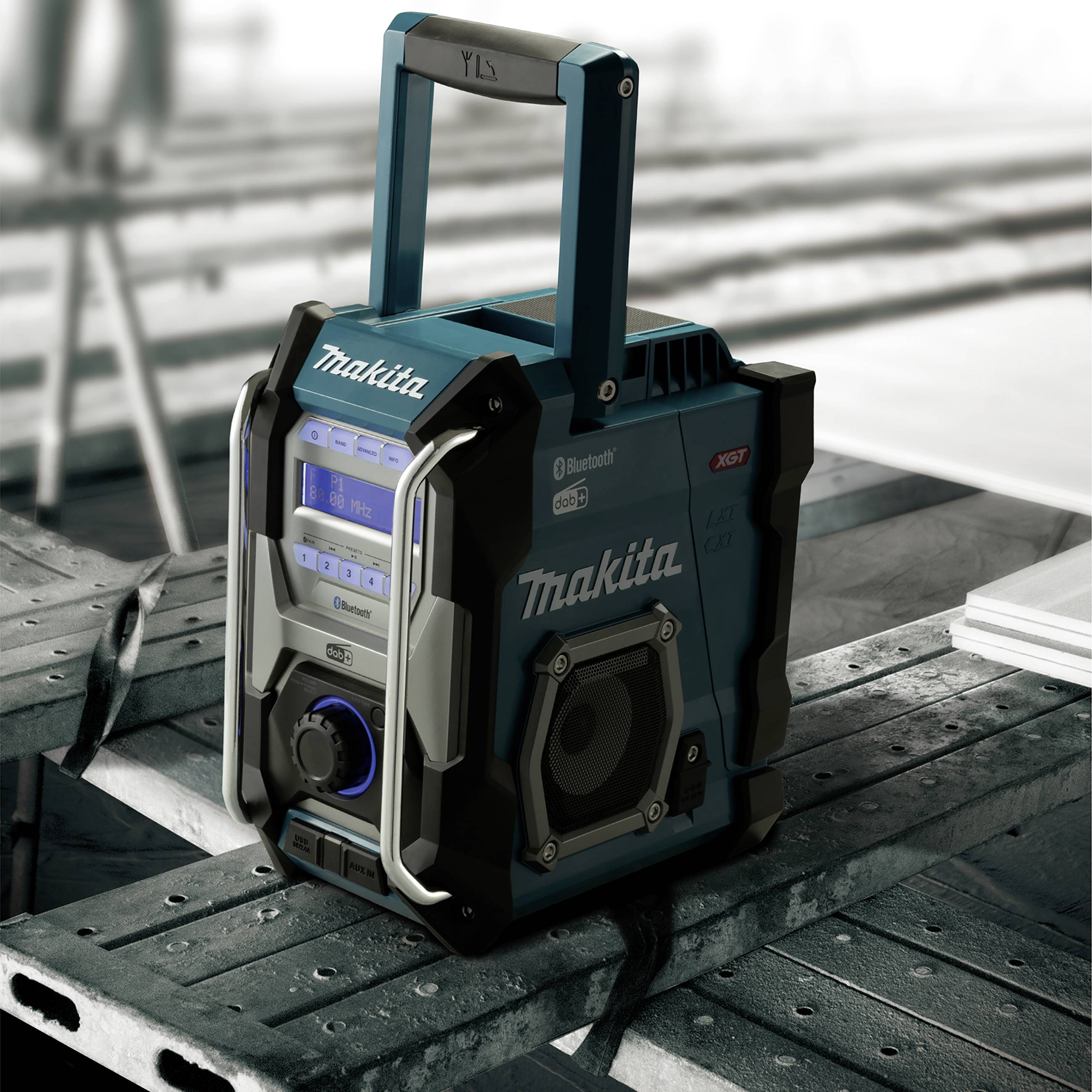 Prenosni, trpežni radio Makita stoji na gradbeni mizi. Ima funkcijo Bluetooth in je idealen za uporabo na gradbiščih.