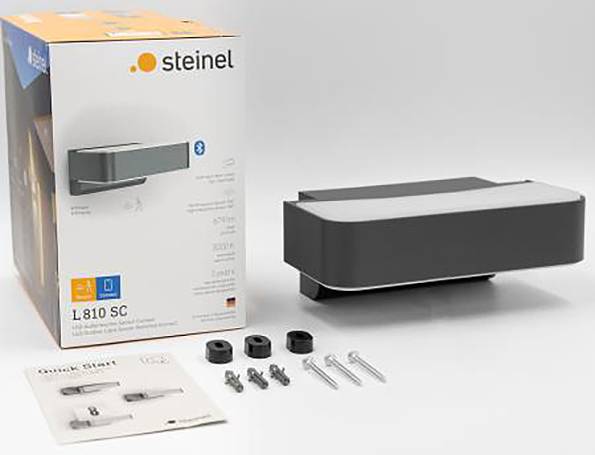 Embalaža in posamezni deli zunanje stenske svetilke Steinel z modelno številko L810 SC. Vidno je dodatna oprema in navodila.