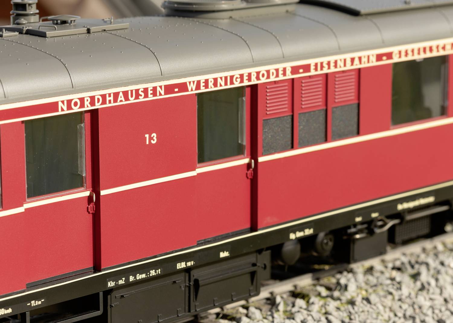 Bližnji posnetek rdečega vagonja vlaka z napisom 'Nordhausen-Wernigerode'. Vagon je prikazan na tirih.