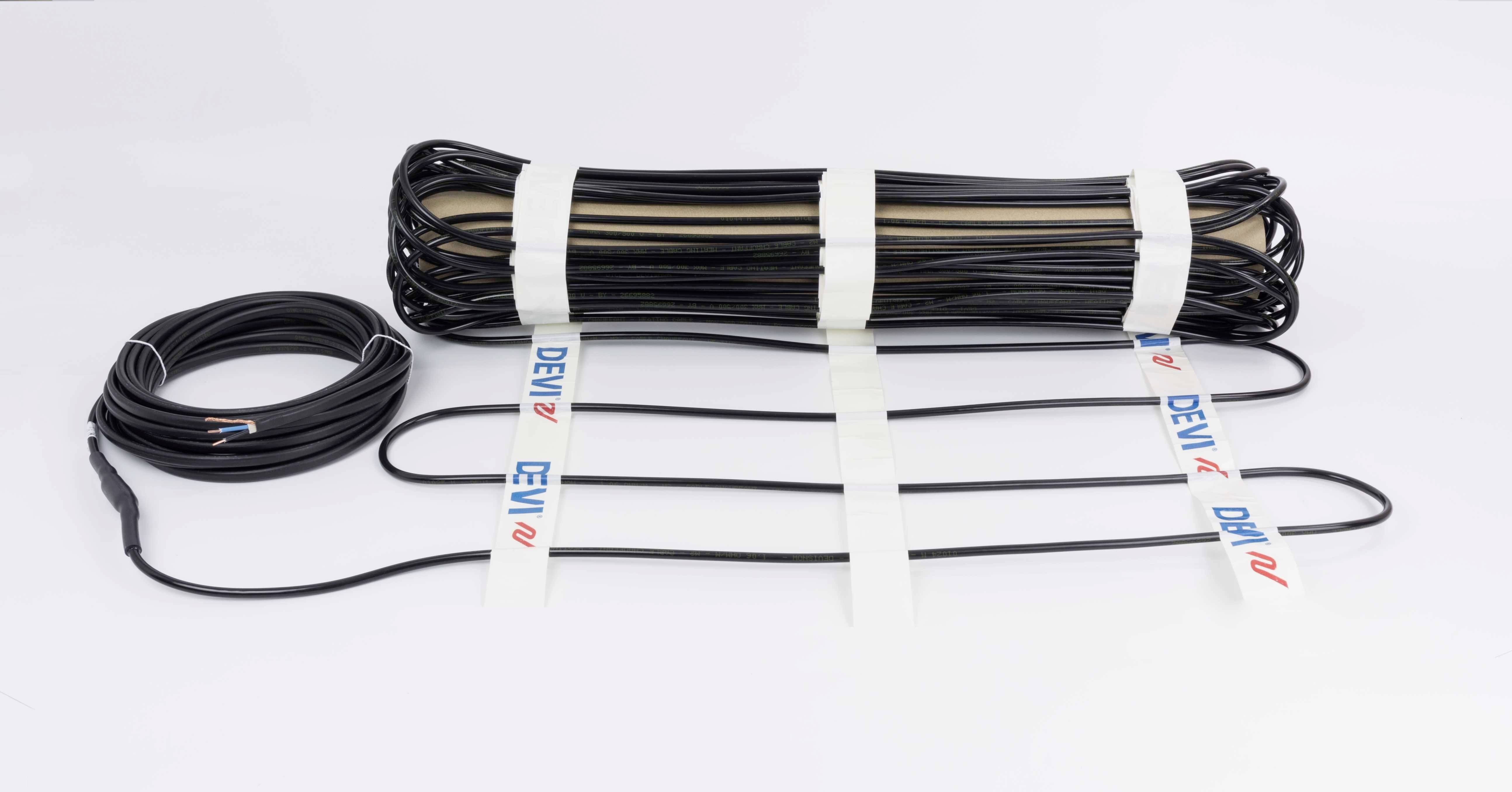 Črn grelni kabel na beli podlagi, delno zvit, s štirimi izstopajočimi priključki. Blagovna znamka 'DEVI' je vidna.