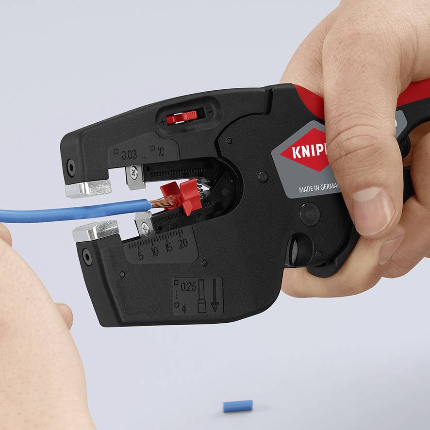 Ena roka drži luščilec žic znamke 'Knipex', ki lušči modri električni kabel.
