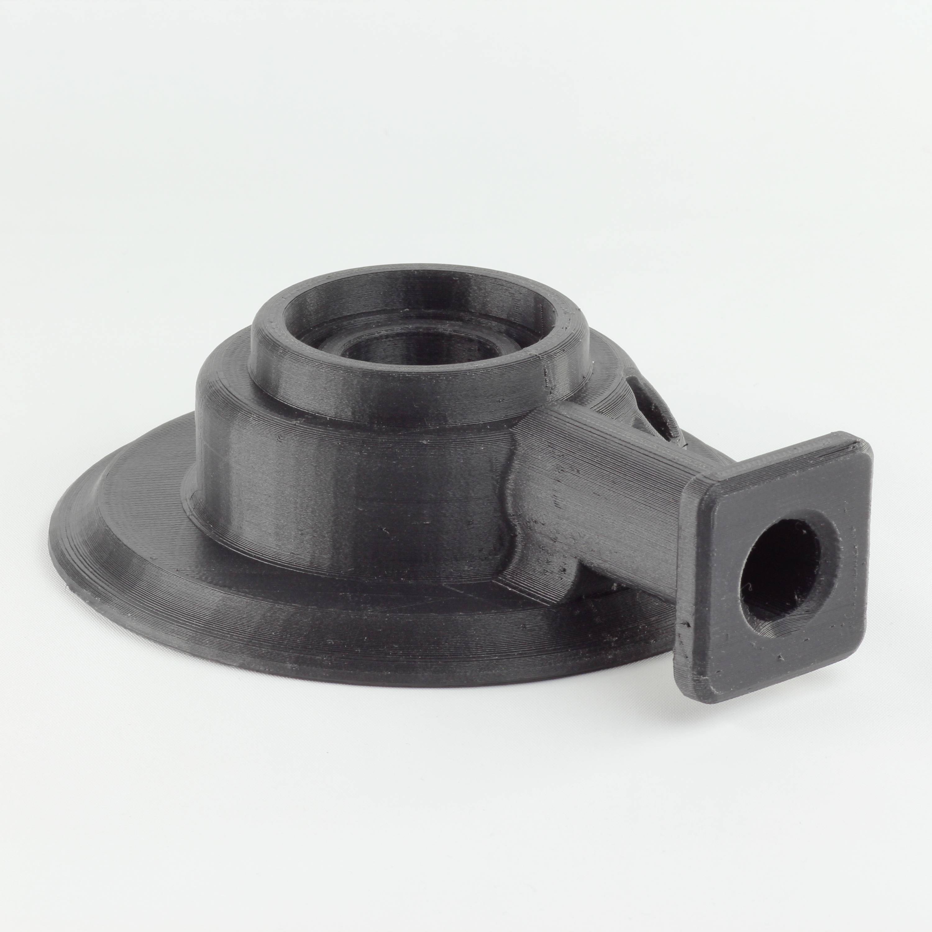Črn, okrogel plastični element z prirobnico in pravokotnim priključkom, verjetno adapter ali nosilec.