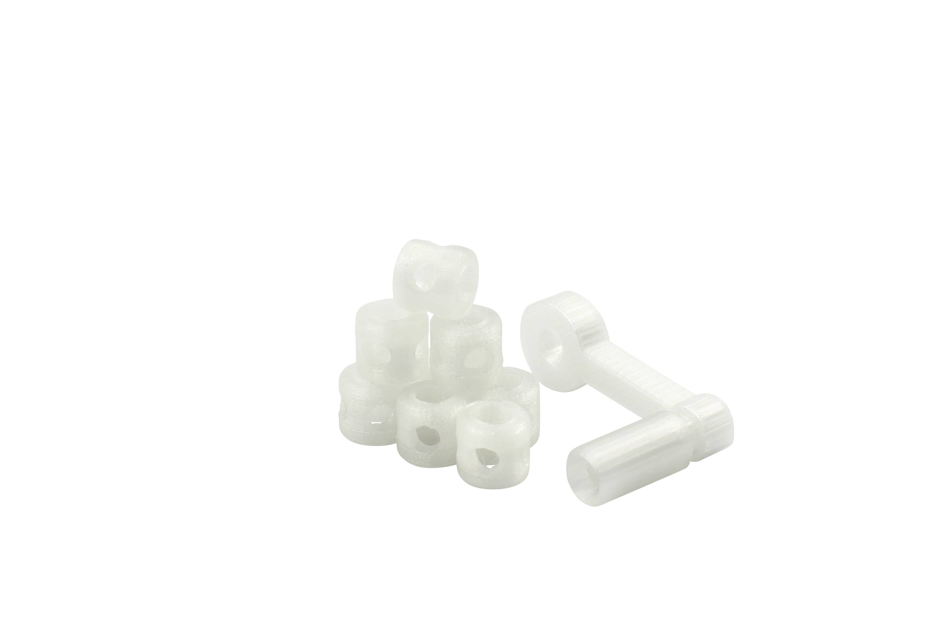 Beli plastični distančniki in vijaki na beli podlagi.