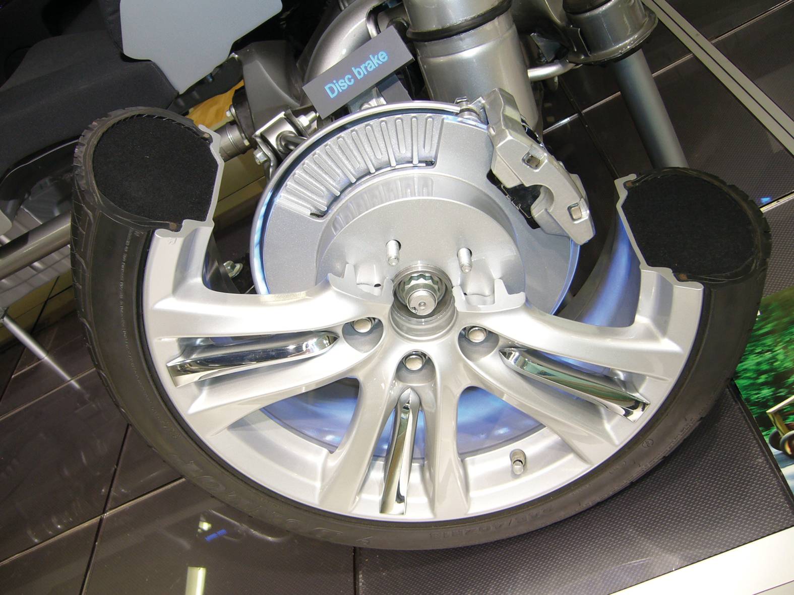 Prečni prerez avtomobilske pnevmatike prikazuje vzmetenje kolesa in zavorni disk. Ponazarja tehniko vzmetenja kolesa.