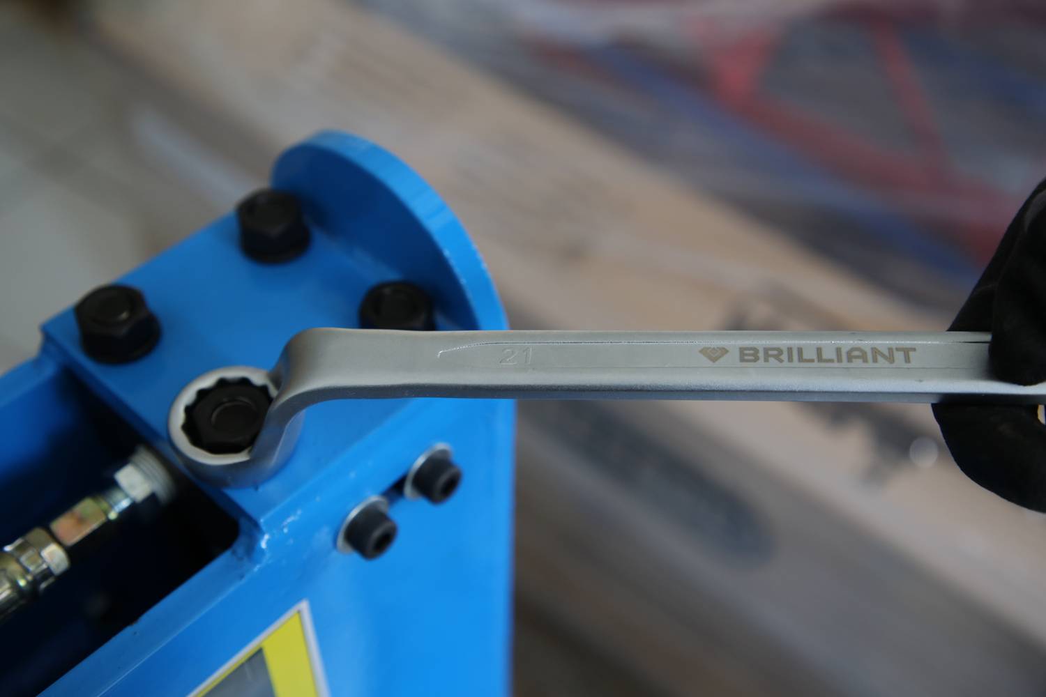 Ključ v roki se uporablja za privitje vijaka na modri napravi.