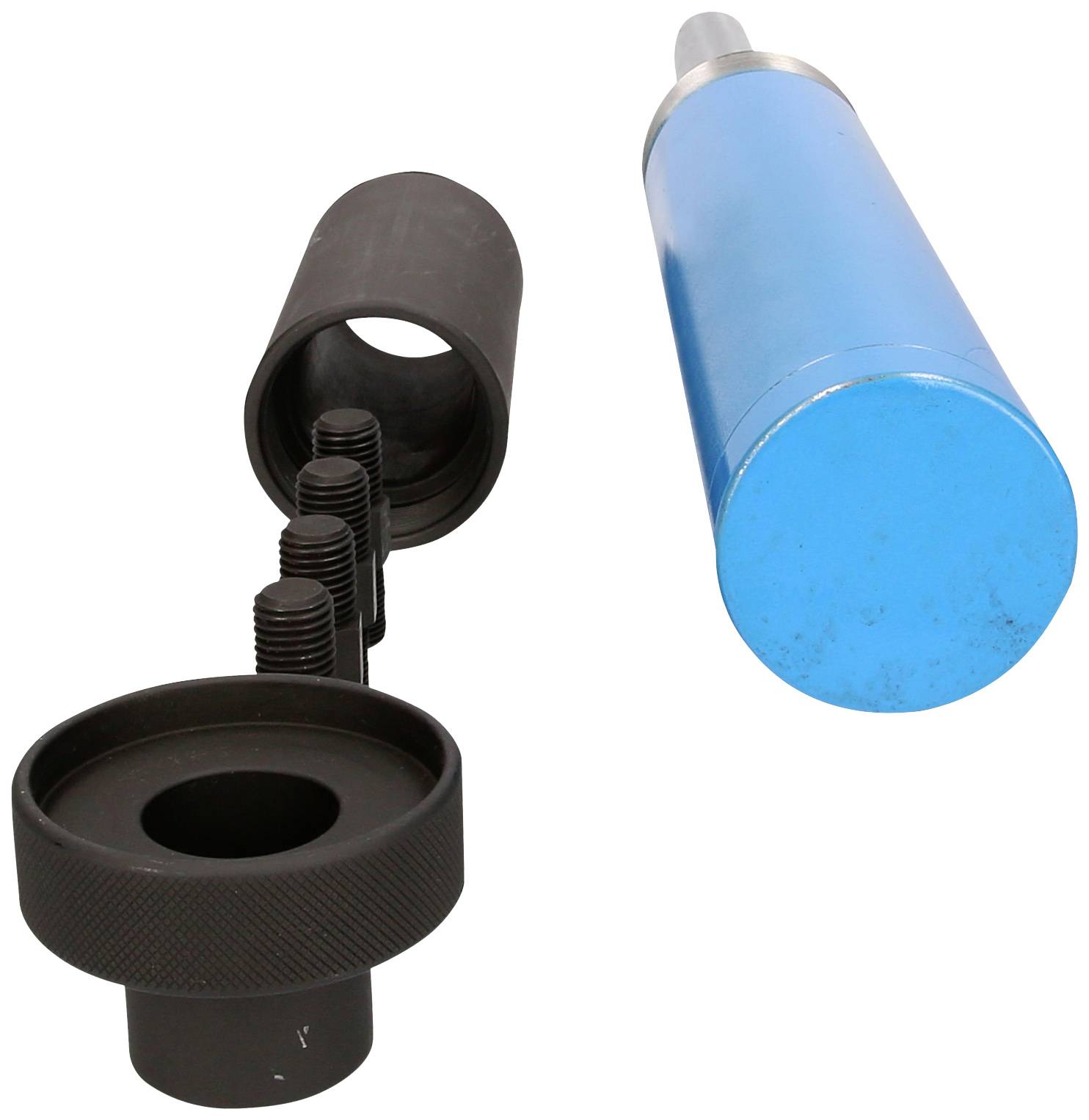 Valj z modrim ohišjem leži poleg črne, votle lupine in narebričenega vijaka. Lahko bi šlo za dele mehanične naprave.