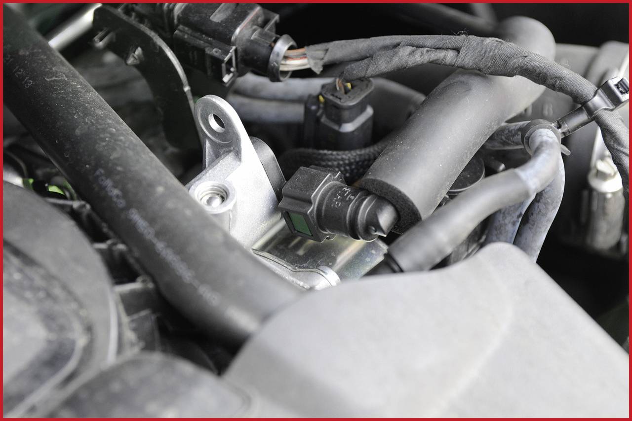 Bližnji posnetek motorja avtomobila, ki prikazuje različne kable in priključke, ki so med seboj povezani. Pretežno tehnične komponente.