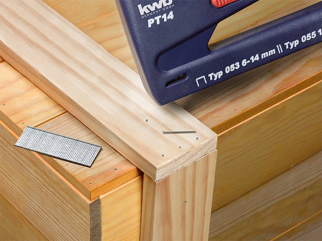 Leseni okvir je pritrjen s sponkami in žeblji. Poleg leži kup sponk. Besedilo na spončniku: 'Tip 053 6-14 mm'.