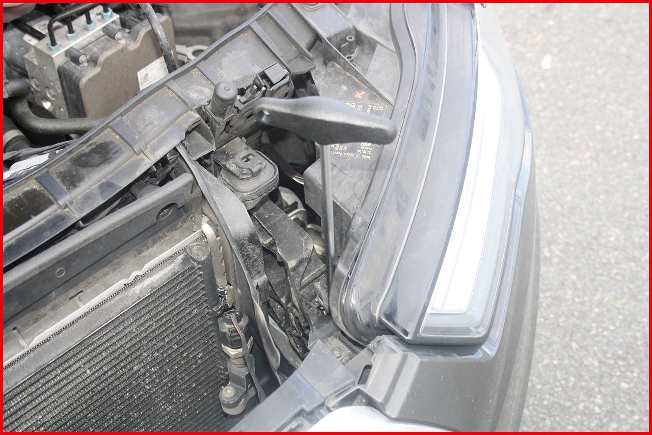 Avtomobil z odprto pokrov motorja prikazuje področje žarometov in dele motorja. Viden je tudi smernik.