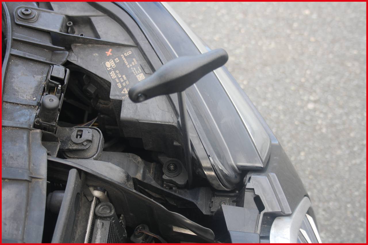 Bližnji posnetek avtomobilskega dela z izpostavljenimi kabli, vidnimi pod dvignjeno pokrovom motorja.