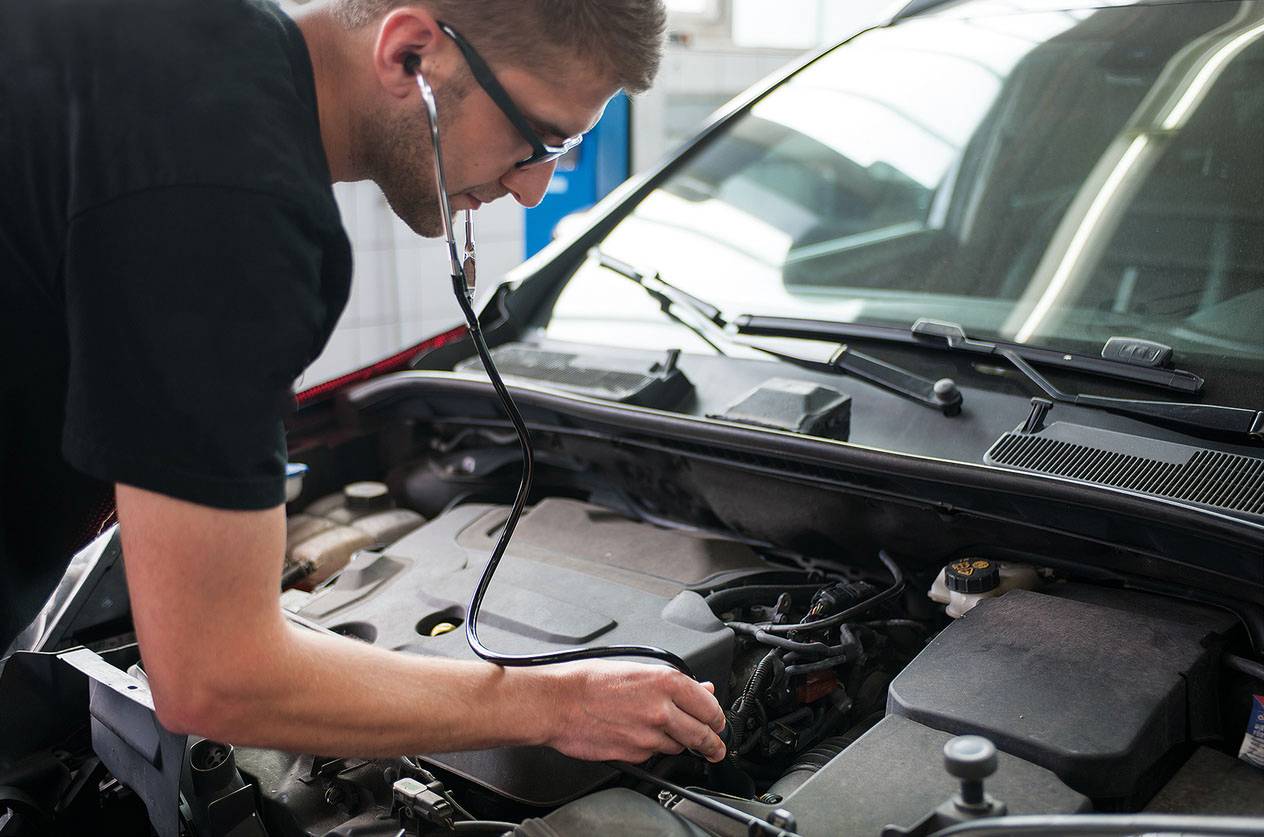 Mehanik s stetoskopom pregleduje motor avtomobila, da bi analiziral zvoke.
