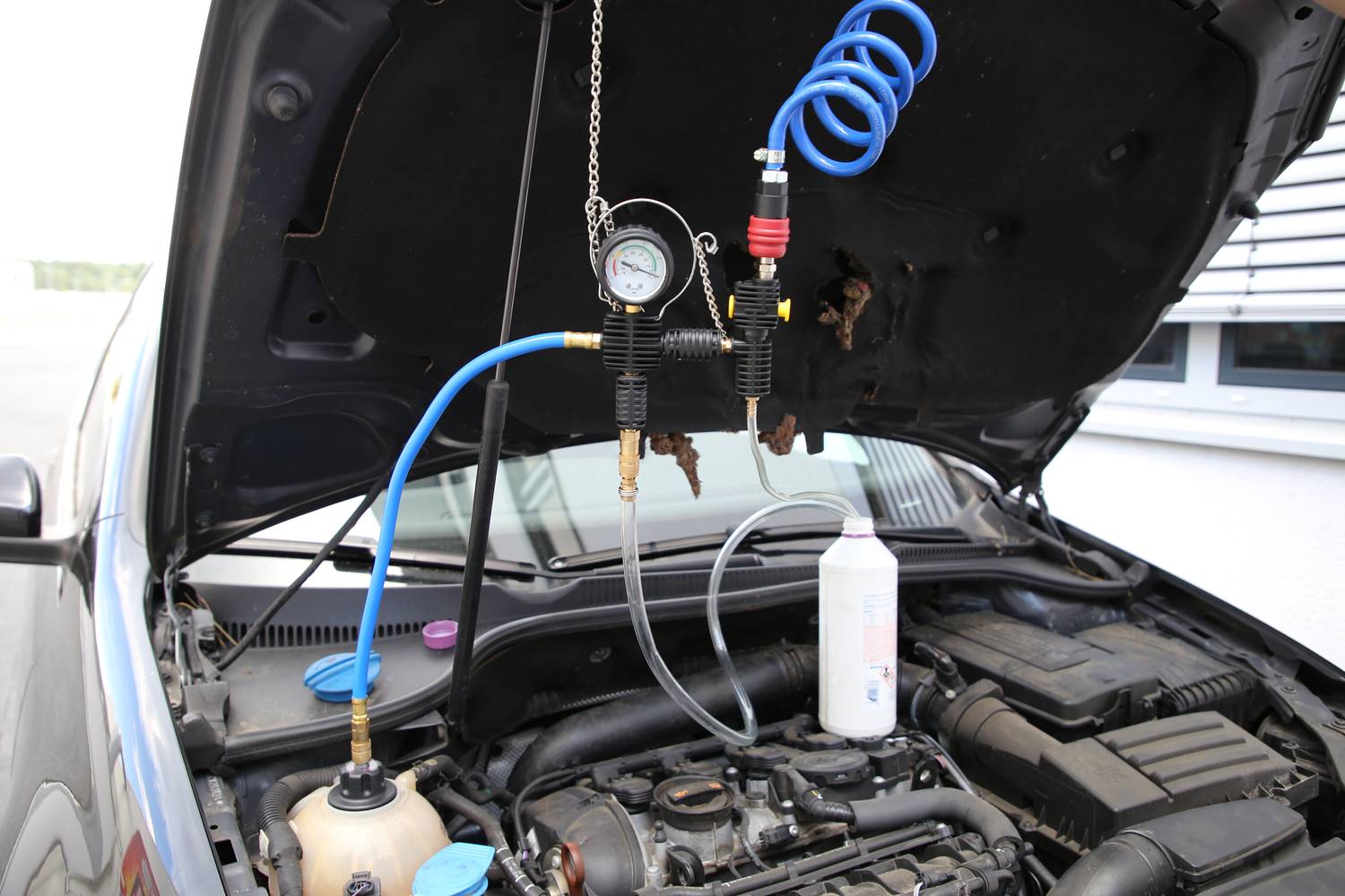 Avtomobil z odprtim pokrovom motorja. Sistem za komprimirani zrak in merilna naprava sta priključena za testiranje delovanja motorja.