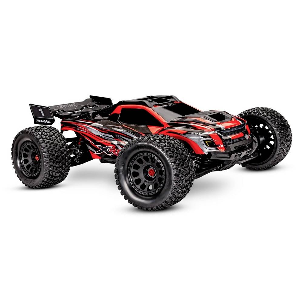 RC-avto z rdečim in črno-belim vzorcem, velikim spoilerjem, grobimi pnevmatikami, na beli podlagi.