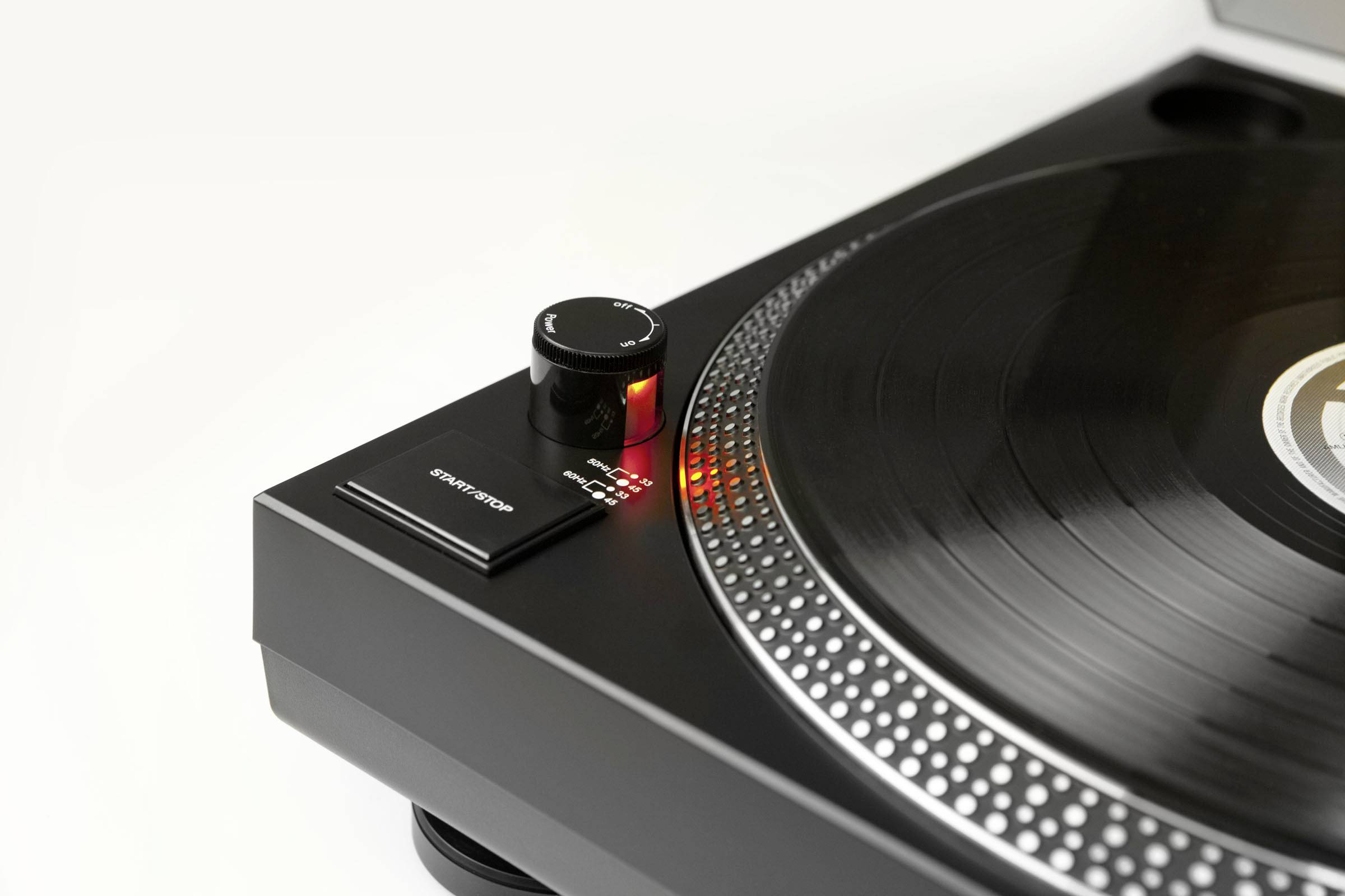 Gramofon s črno vinilno ploščo na krožniku. Bližnji posnetek prikazuje regulator hitrosti z osvetljeno LED-lučko.