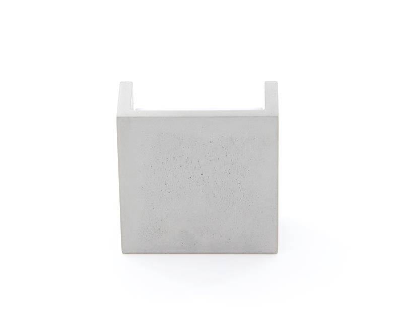 Minimalistični designerski predmet iz betona v kubični strukturi, verjetno dekorativni element ali kos pohištva.