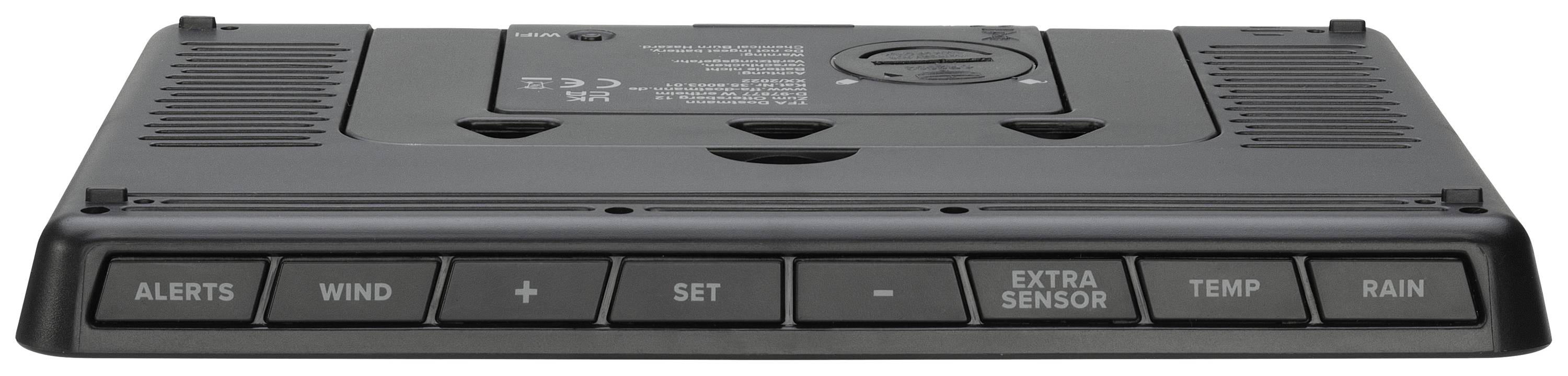 Črna digitalna vremenska postaja s tipkami: 'Opozorila', 'Veter', '+', 'Nastavi', '-', 'Dodatni senzor', 'Temperatura', 'Dež'.