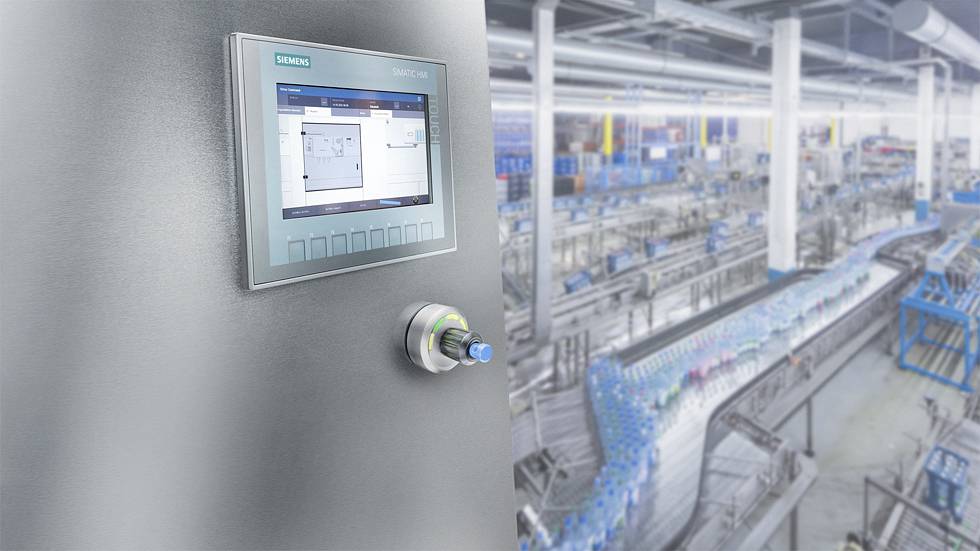 Industrijski tovarniški prostor s poudarkom na Siemensovi krmilni plošči v ospredju, ki prikazuje proizvodne podatke na zaslonu.