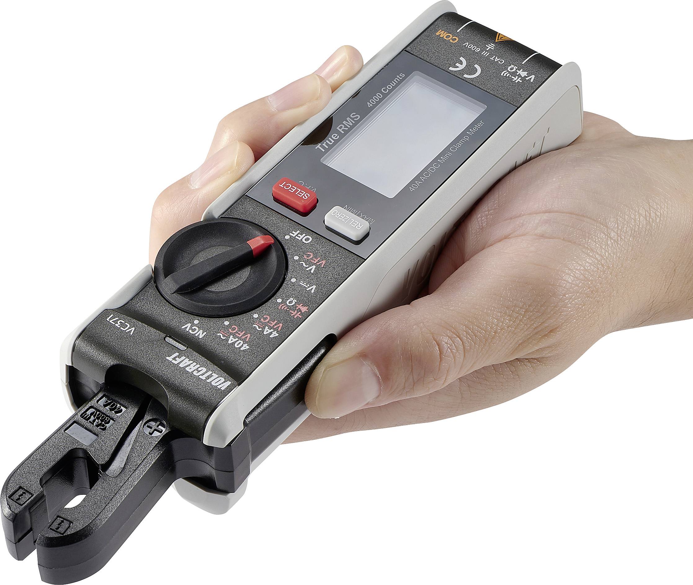 Nekdo drži prenosni digitalni multimeter z zaslonom in obračalnim stikalom. Primeren je za merjenje napetosti in toka.