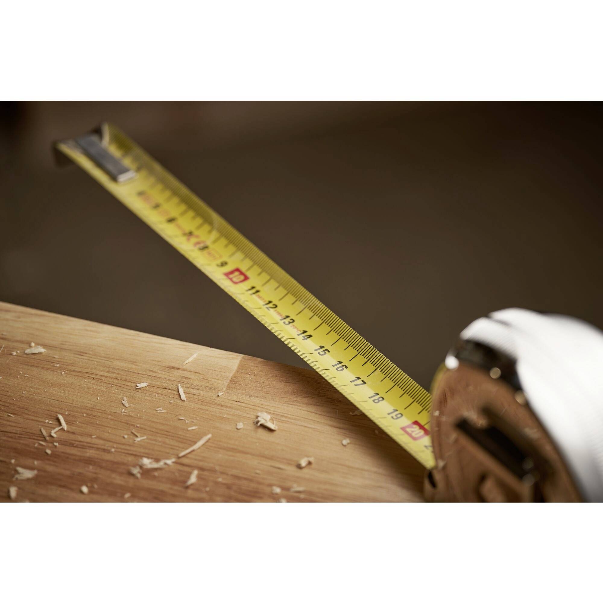 Merilni trak je razprostrt na leseni mizi, obdan z lesnimi opilki.