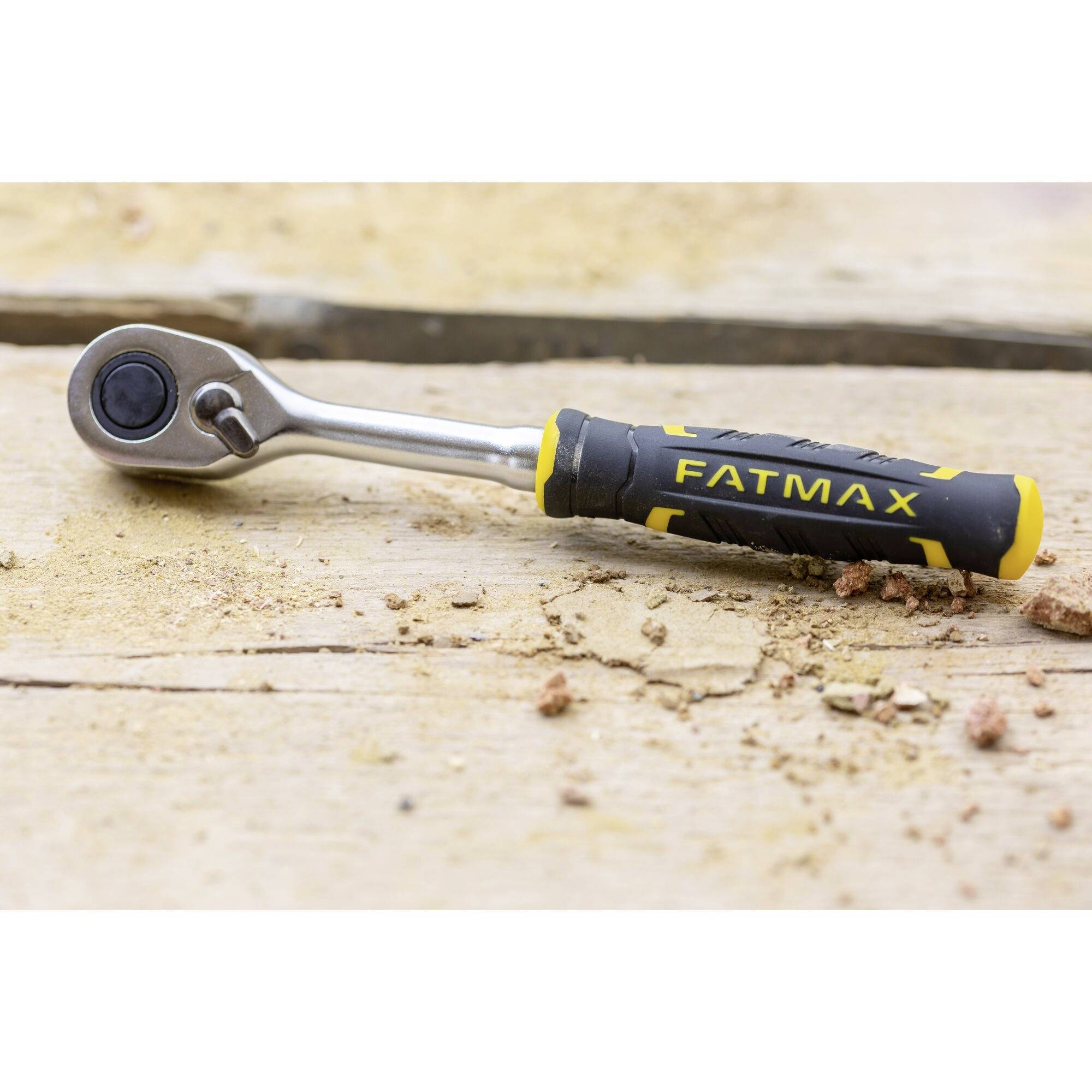 Majhen vijačni ključ z črnim in rumenim ročajem leži na leseni površini.