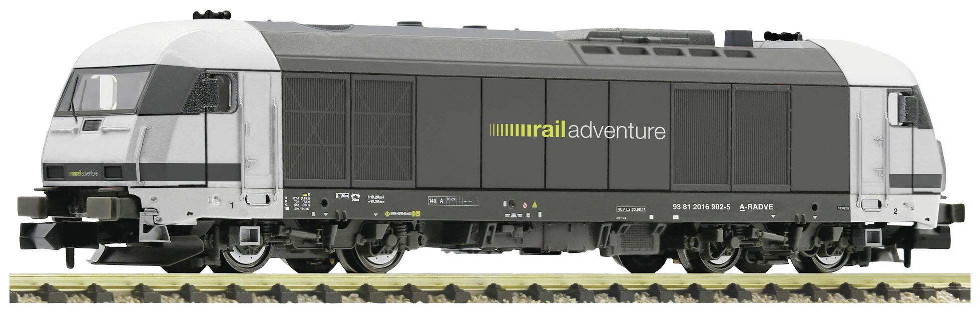 Moderna lokomotiva z napisom 'rail adventure' na strani stoji na tirih. Dizajn je črno-bel.