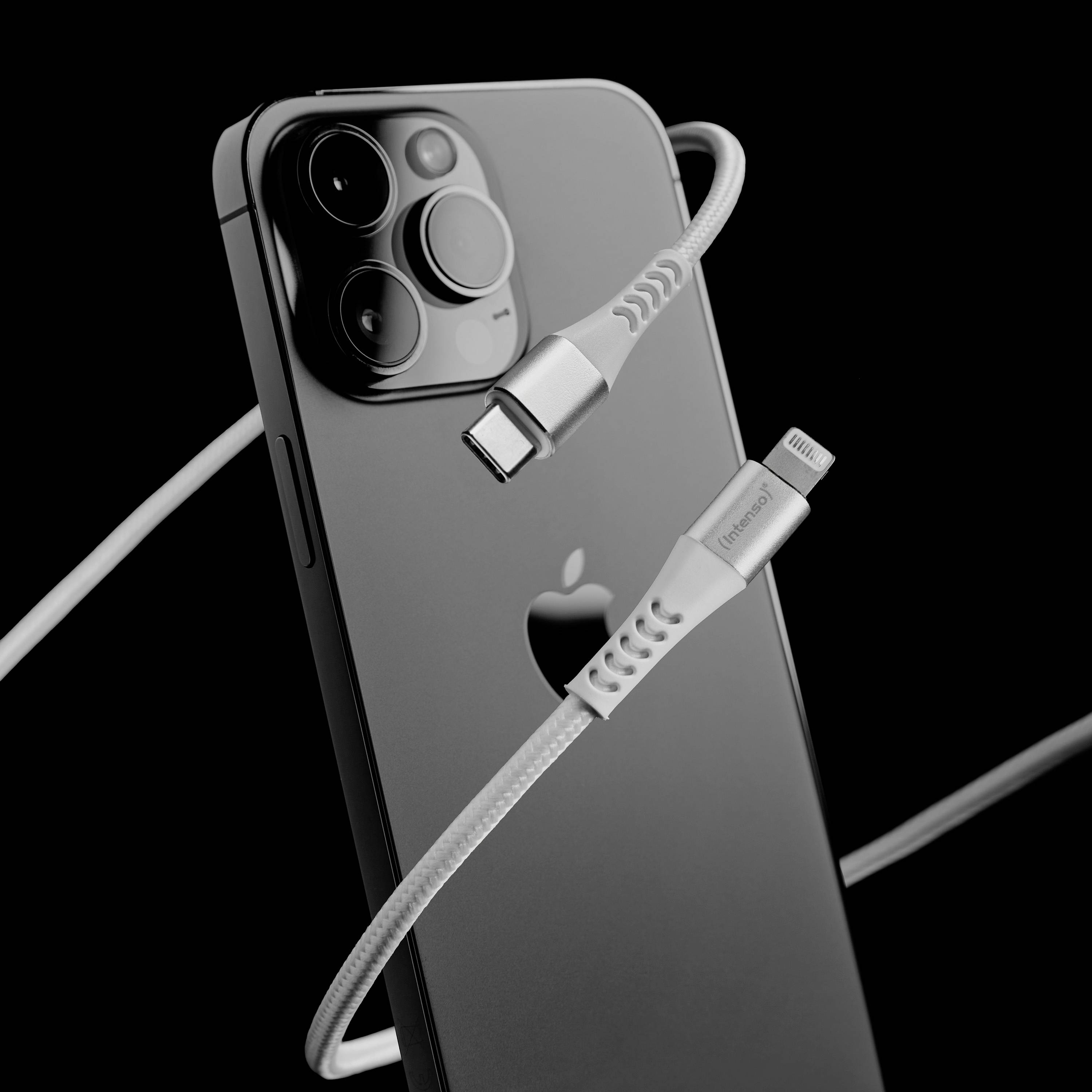 Sodoben črn pametni telefon s tremi kamerami je v ospredju. Zraven je videti polnilni kabel z Lightning priključkom.