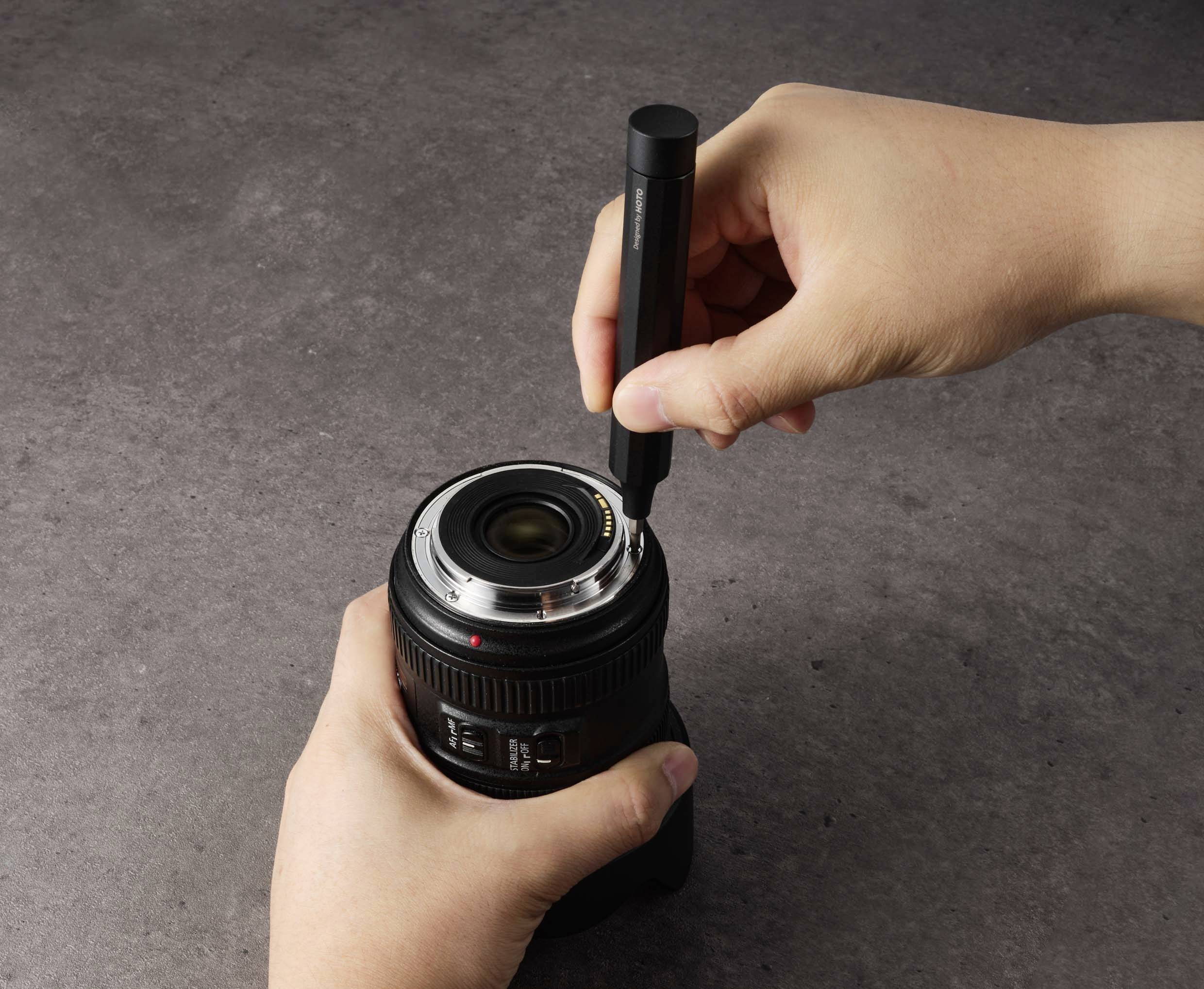 Oseba čisti objektiv fotoaparata s posebnim svinčnikom.