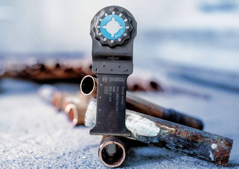 Na sliki je prikazano multifunkcijsko žaginsko rezilo, vstavljeno v bakreno obarvan cev. Prikazuje vsestranskost funkcije rezanja.