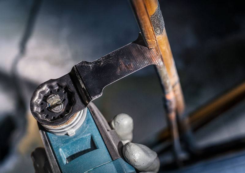 Oseba z kotno brusilko reže bakreno cev, pri čemer letijo iskre. Gre za obrtniško dejavnost.