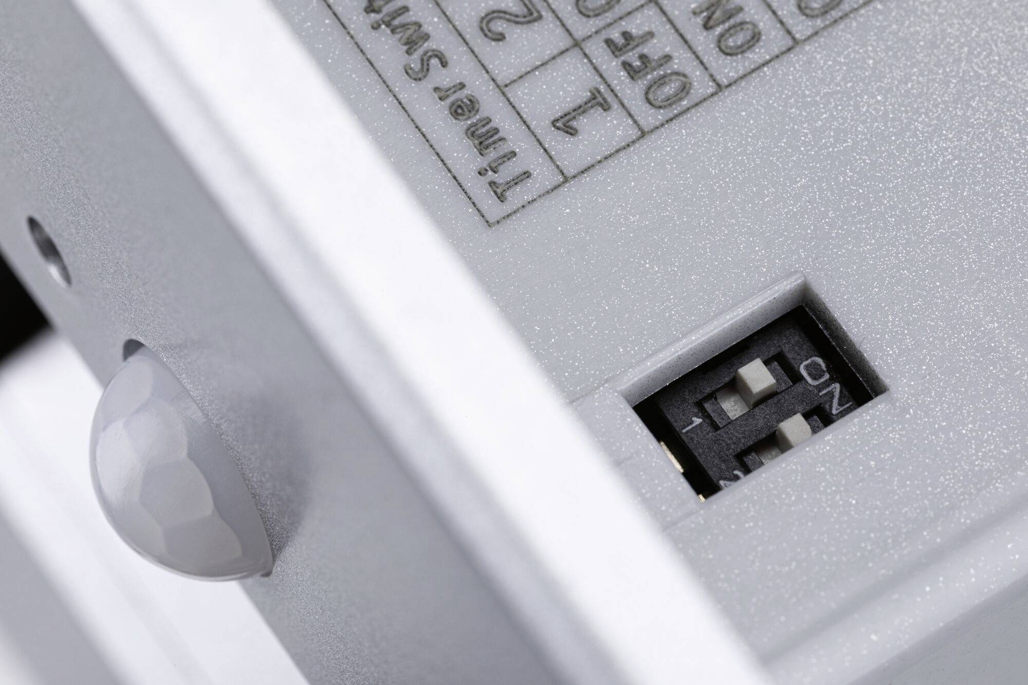 Bližnji posnetek električnega stikala s senzorjem gibanja in majhnim stikalom s tremi nastavitvami.