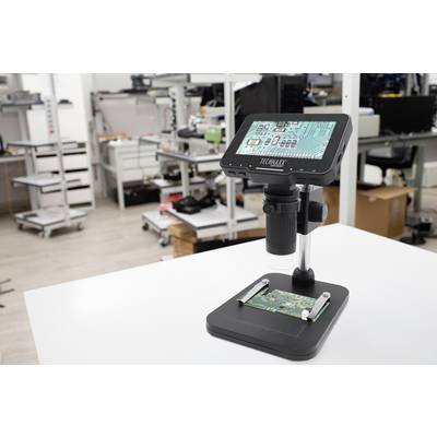 Digitalni mikroskop na mizi v tehničnem laboratoriju s tiskanim vezjem pod lečo. V ozadju so različne delovne postaje.