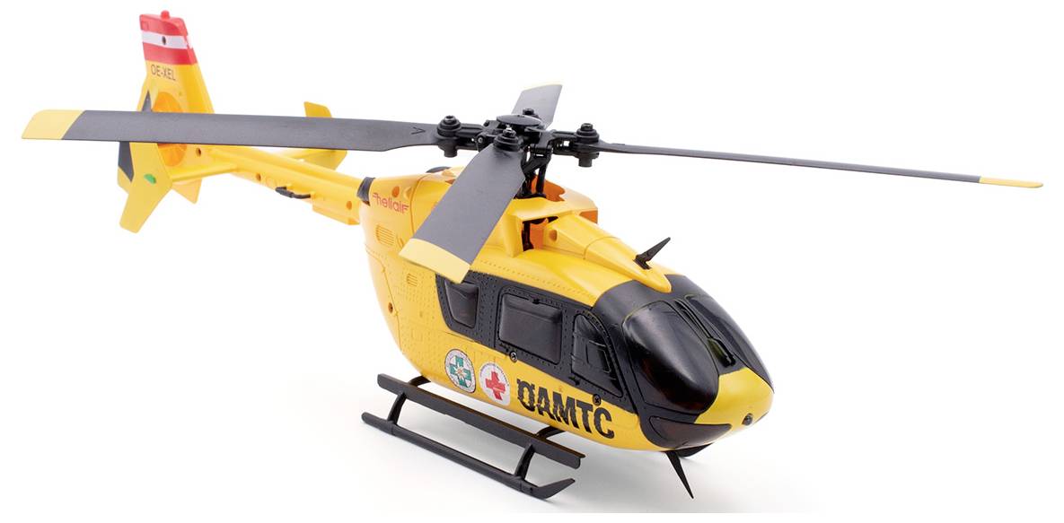 Rumeni reševalni helikopter z logotipom ÖAMTC in medicinskimi simboli na strani stoji na belem ozadju.