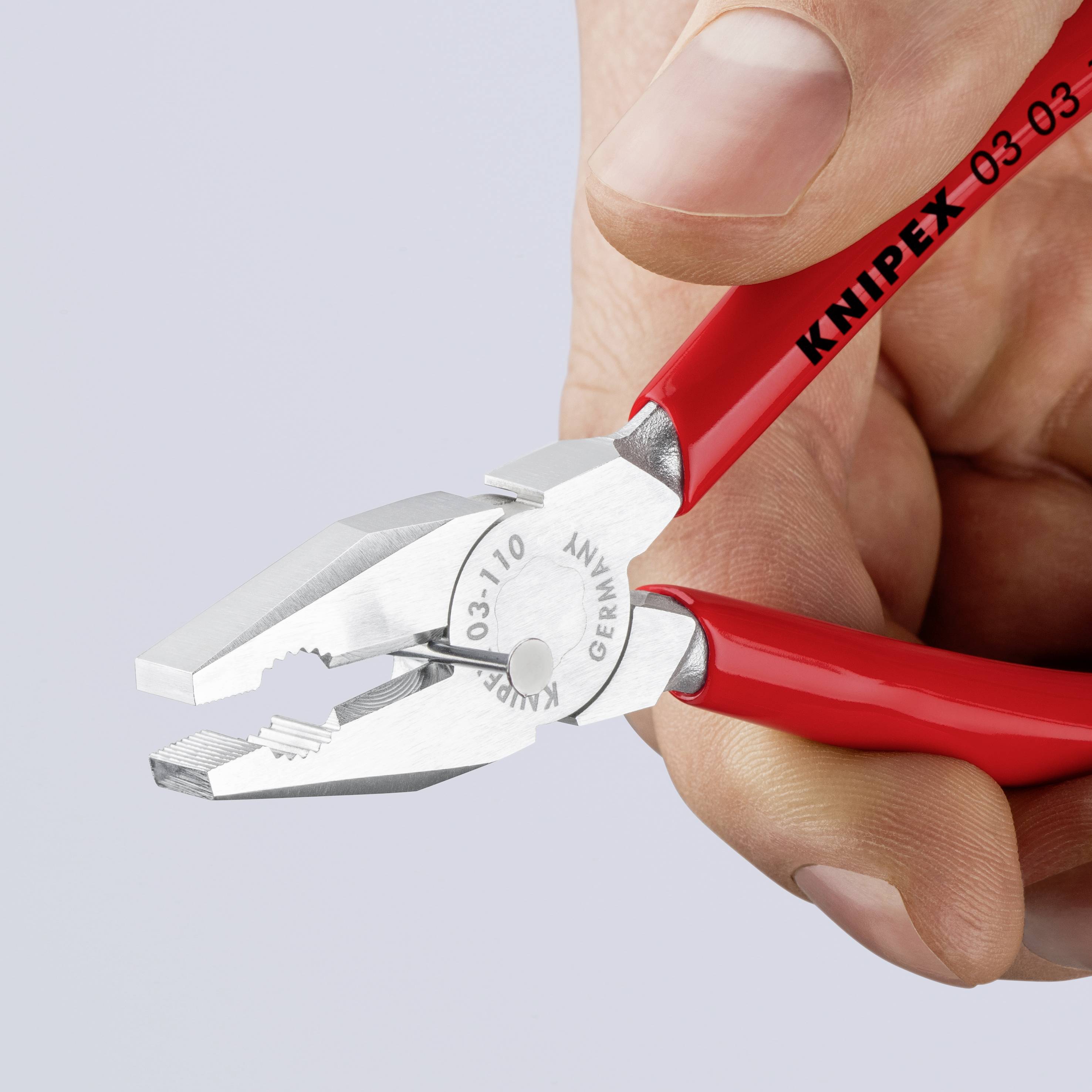 Roka drži rdečo kombinirano klešče. Na kleščah piše 'KNIPEX' in 'Made in Germany'.