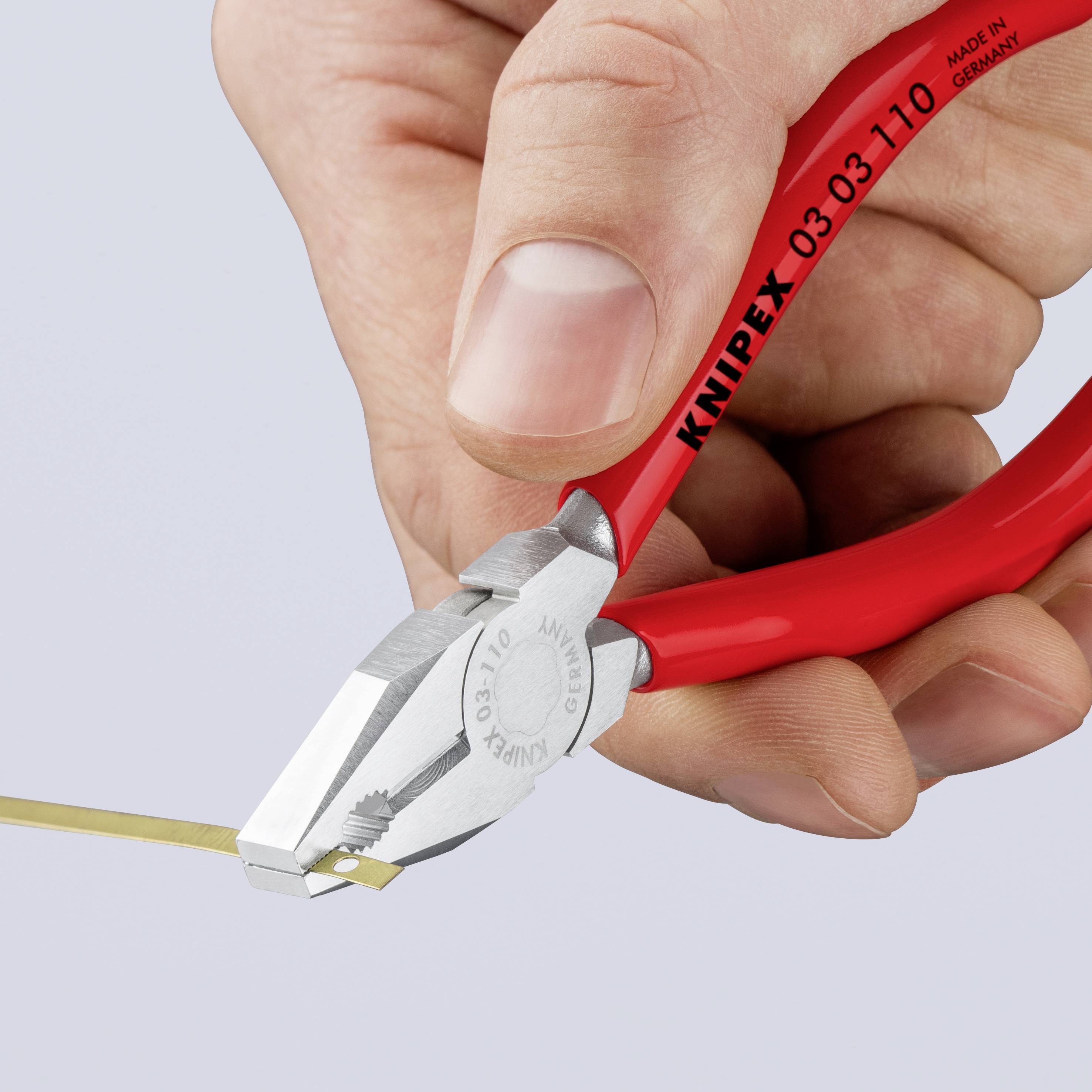 Roka drži rdeče bočne klešče Knipex in prereže tanek žico.
