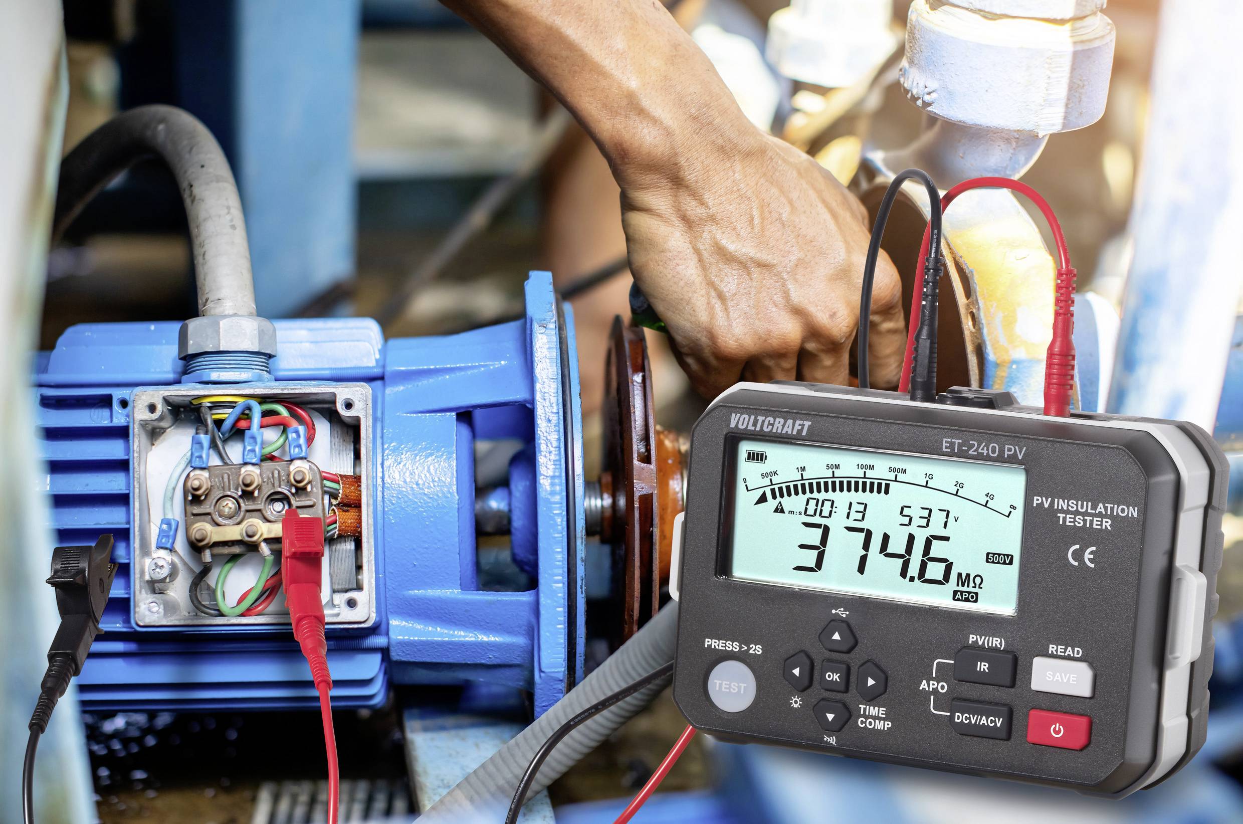 Oseba uporablja digitalni merilnik izolacije na električnem motorju. Merilnik prikazuje '3746 MΩ', kar nakazuje meritev upora.