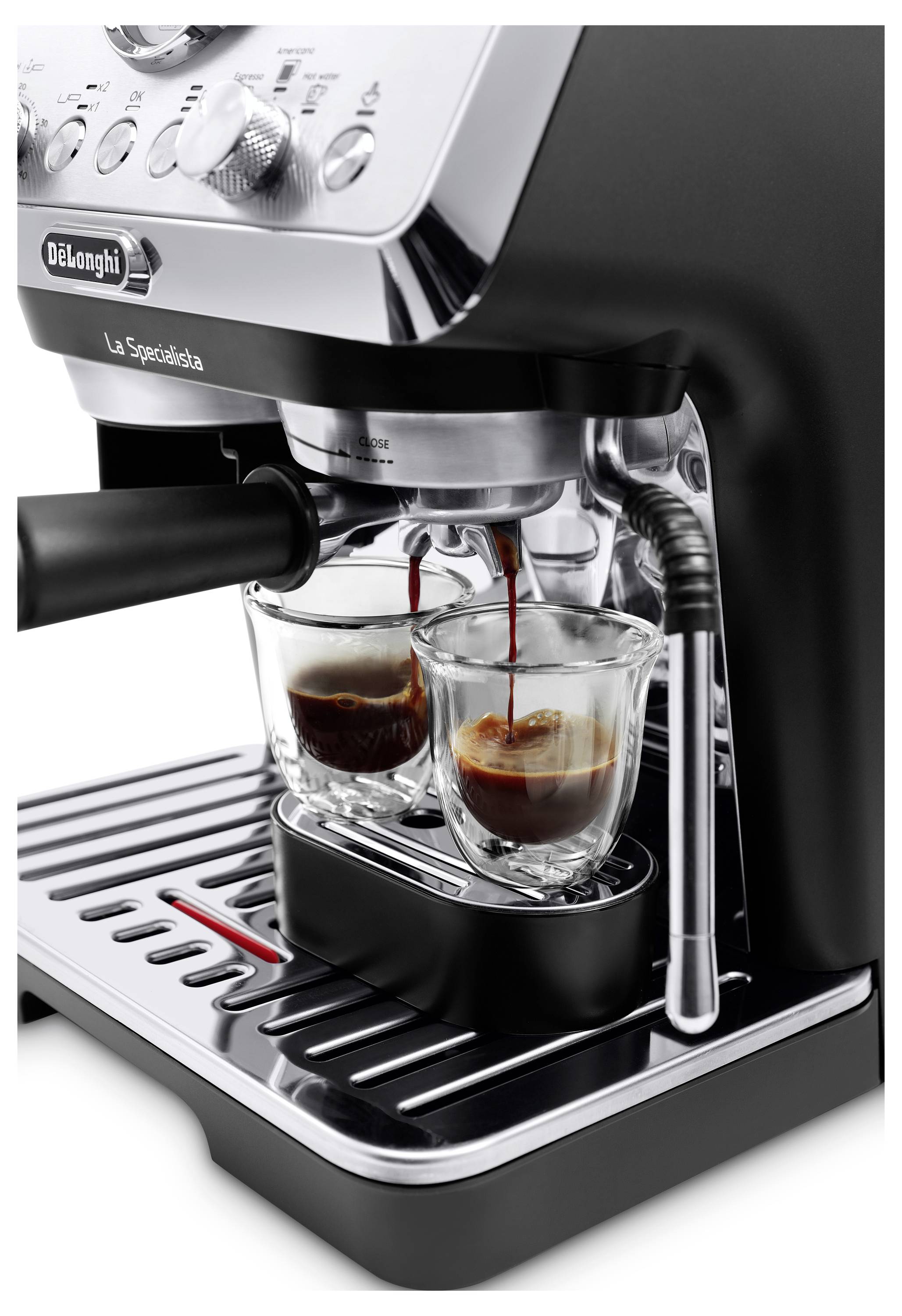 Kavni aparat espresso, ki naliva kavo v dve stekleni skodelici na kapalni pladnju. Aparat ima kromiran finish in črne poudarke.