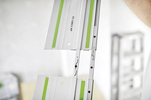 Bližnji posnetek segmentirane kovinske proge z zelenimi poudarki, verjetno namenjene orodjem ali gradbeništvu, ki prikazuje podrobnosti mehanizma za medsebojno povezovanje.